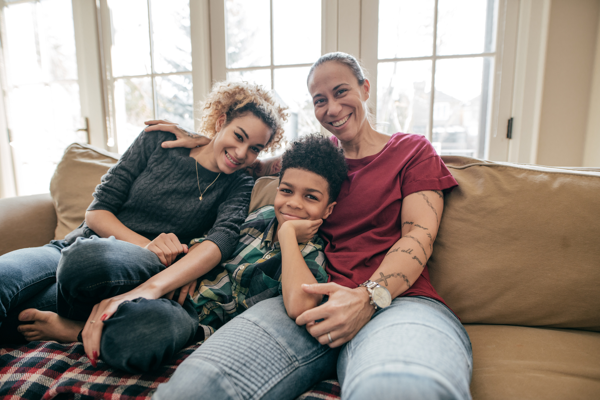 Homosexual couple and a boy sitting and smiling.