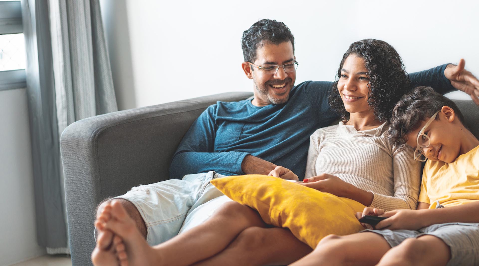 Man and two children smiling on a couch