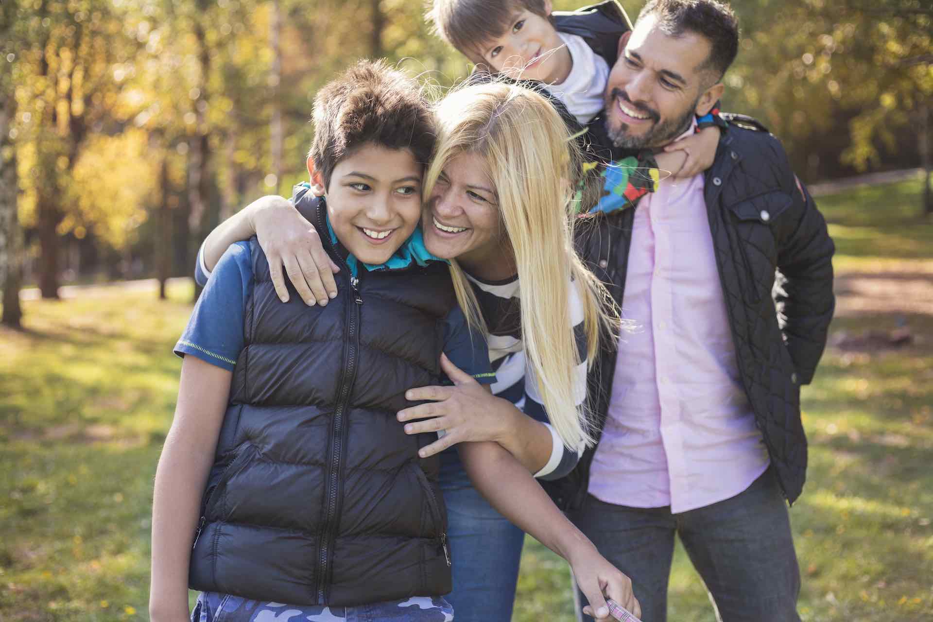 Two adults and two kids smiling in autumn scene outdoors