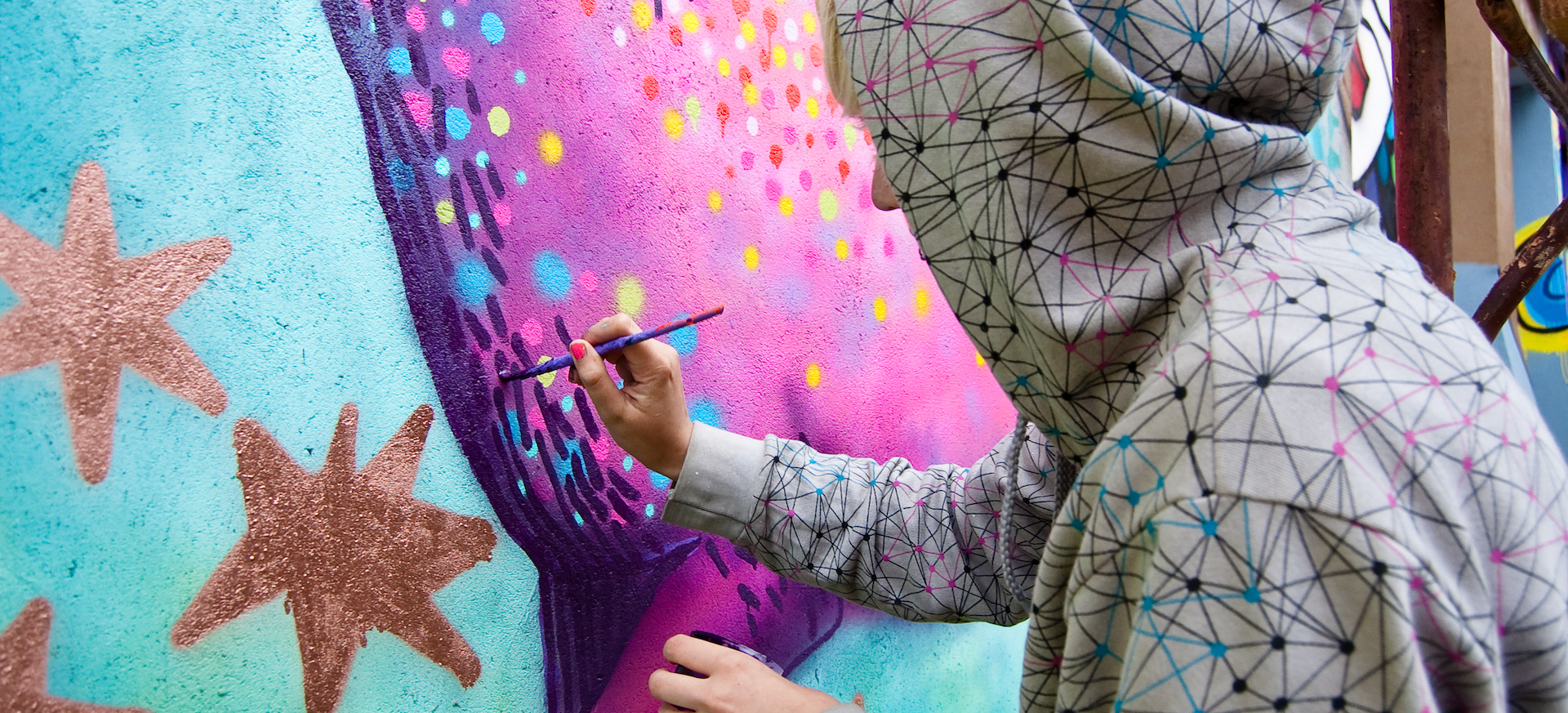 Youth painting brightly-colored mural